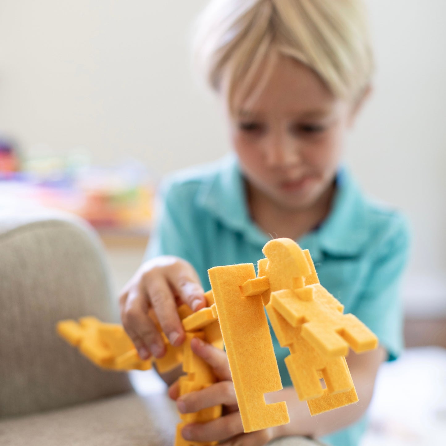 a boy plays with a yellow dinosaur made from Lowercase Toys interlocking blocks.