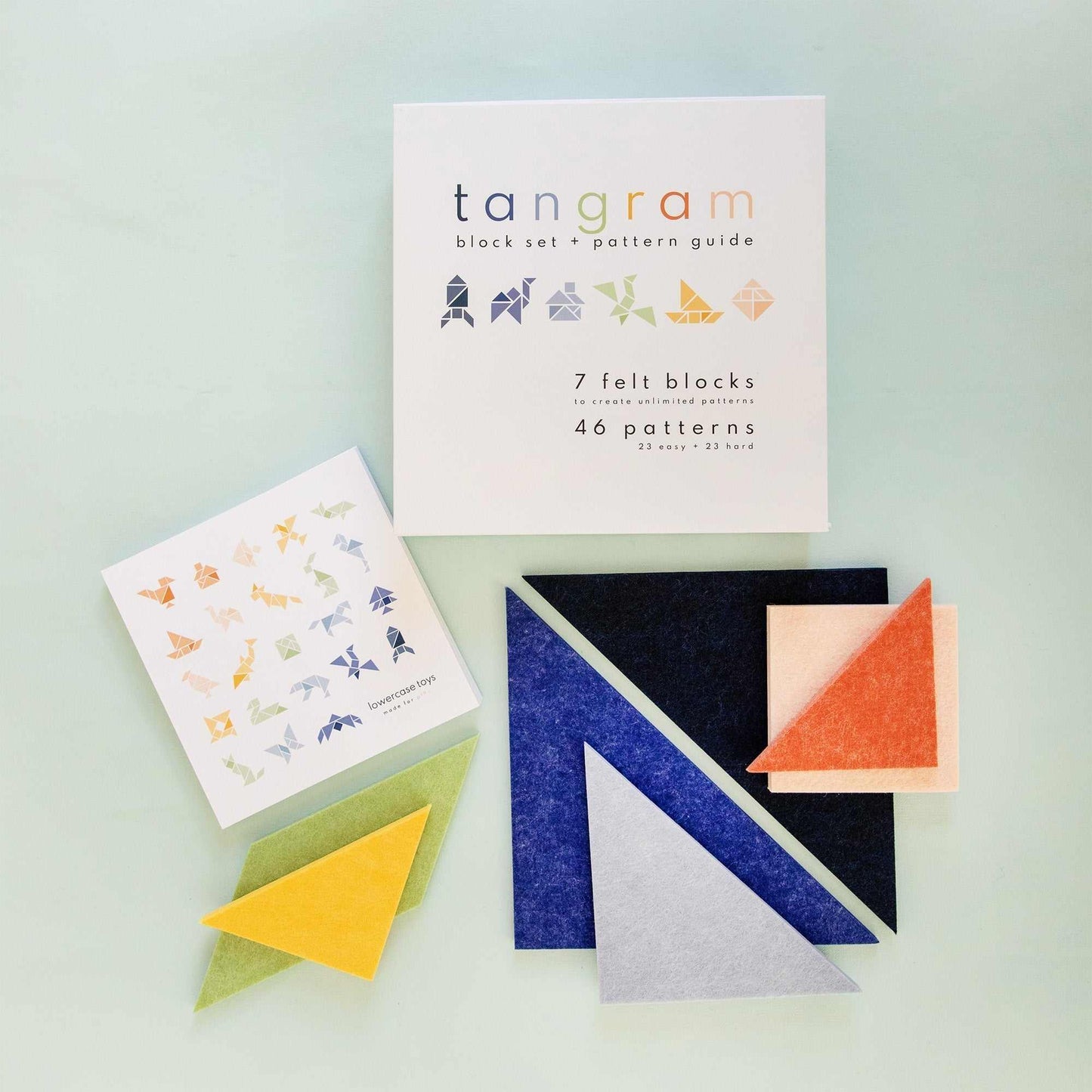 colorful felt tangram building block toy set with pattern guide and geometric shapes on light background