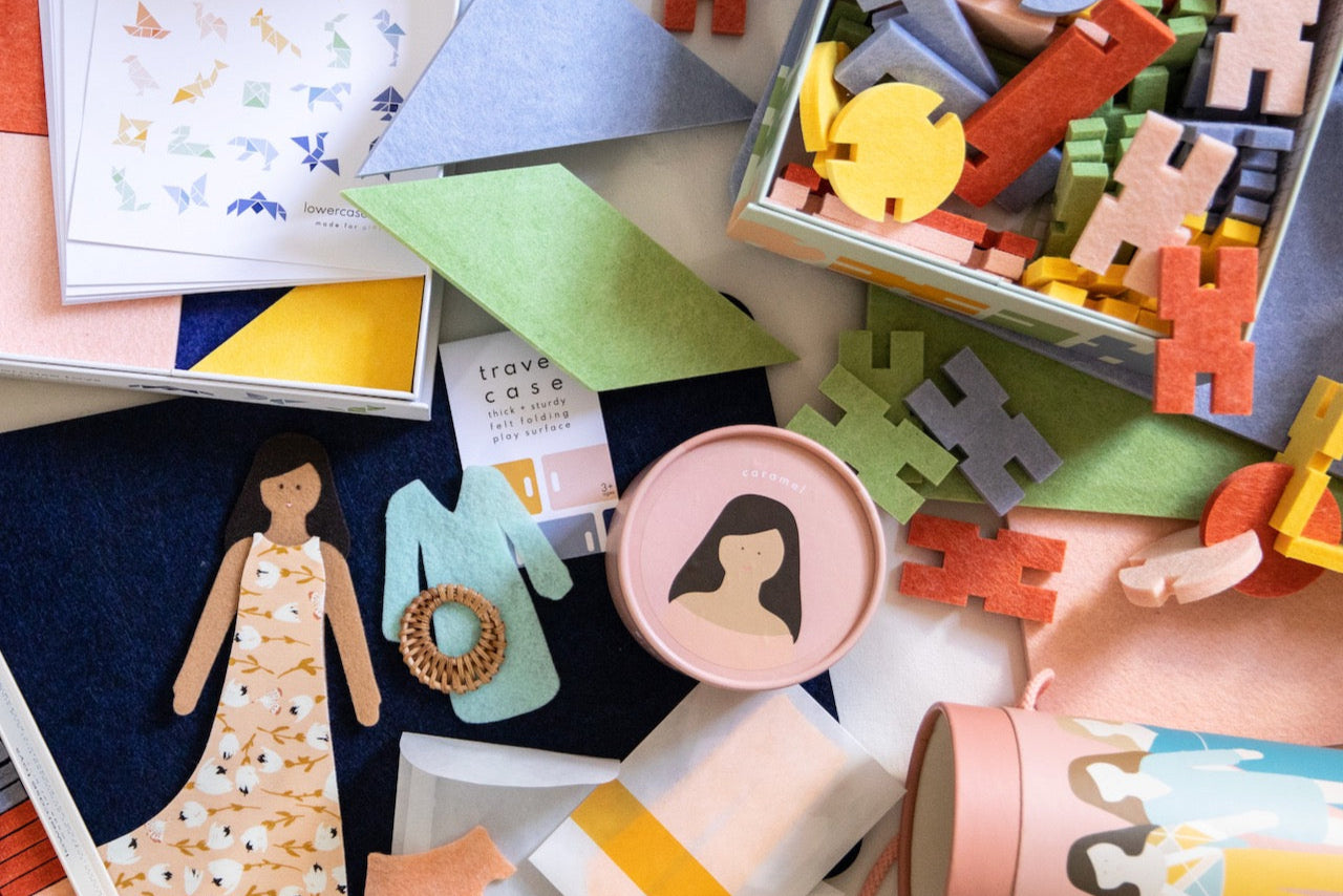 interlocking blocks and felt dolls spread in a play scene.
